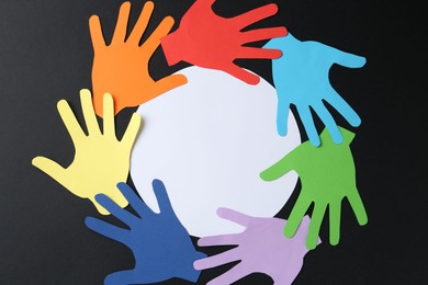 Photo of Tolerance concept. Colorful paper hands and empty card on black background, flat lay. Space for text
