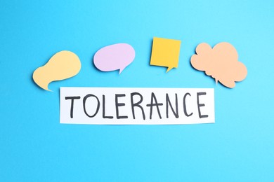 Photo of Card with word Tolerance and speech bubbles on light blue background, flat lay