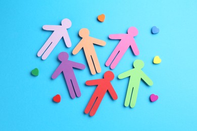 Photo of Tolerance concept. Colorful human figures and hearts on light blue background, flat lay