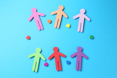 Photo of Tolerance concept. Colorful human figures and hearts on light blue background, flat lay