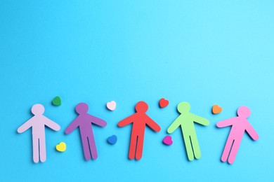 Photo of Tolerance concept. Colorful human figures and hearts on light blue background, flat lay. Space for text