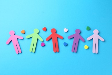 Photo of Tolerance concept. Colorful human figures and hearts on light blue background, flat lay