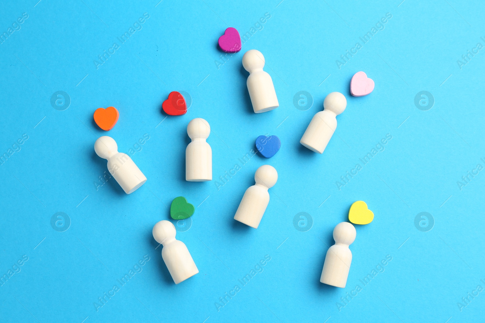 Tolerance concept. Human figures and colorful hearts on light blue background, flat lay Photo of Tolerance concept. Human figures and colorful hearts on light blue background, flat lay