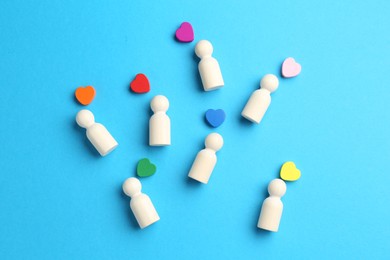Photo of Tolerance concept. Human figures and colorful hearts on light blue background, flat lay