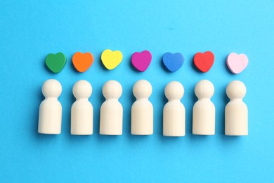 Photo of Tolerance concept. Human figures and colorful hearts on light blue background, flat lay