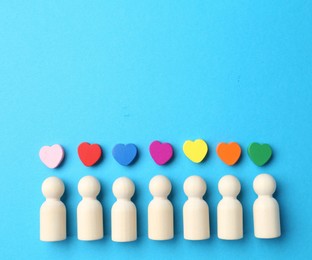 Photo of Tolerance concept. Human figures and colorful hearts on light blue background, flat lay. Space for text