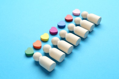 Photo of Tolerance concept. Human figures and colorful hearts on light blue background, closeup