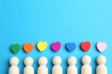 Photo of Tolerance concept. Human figures and colorful hearts on light blue background, flat lay. Space for text