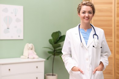 Photo of Portrait of professional pediatrician with stethoscope in hospital. Space for text