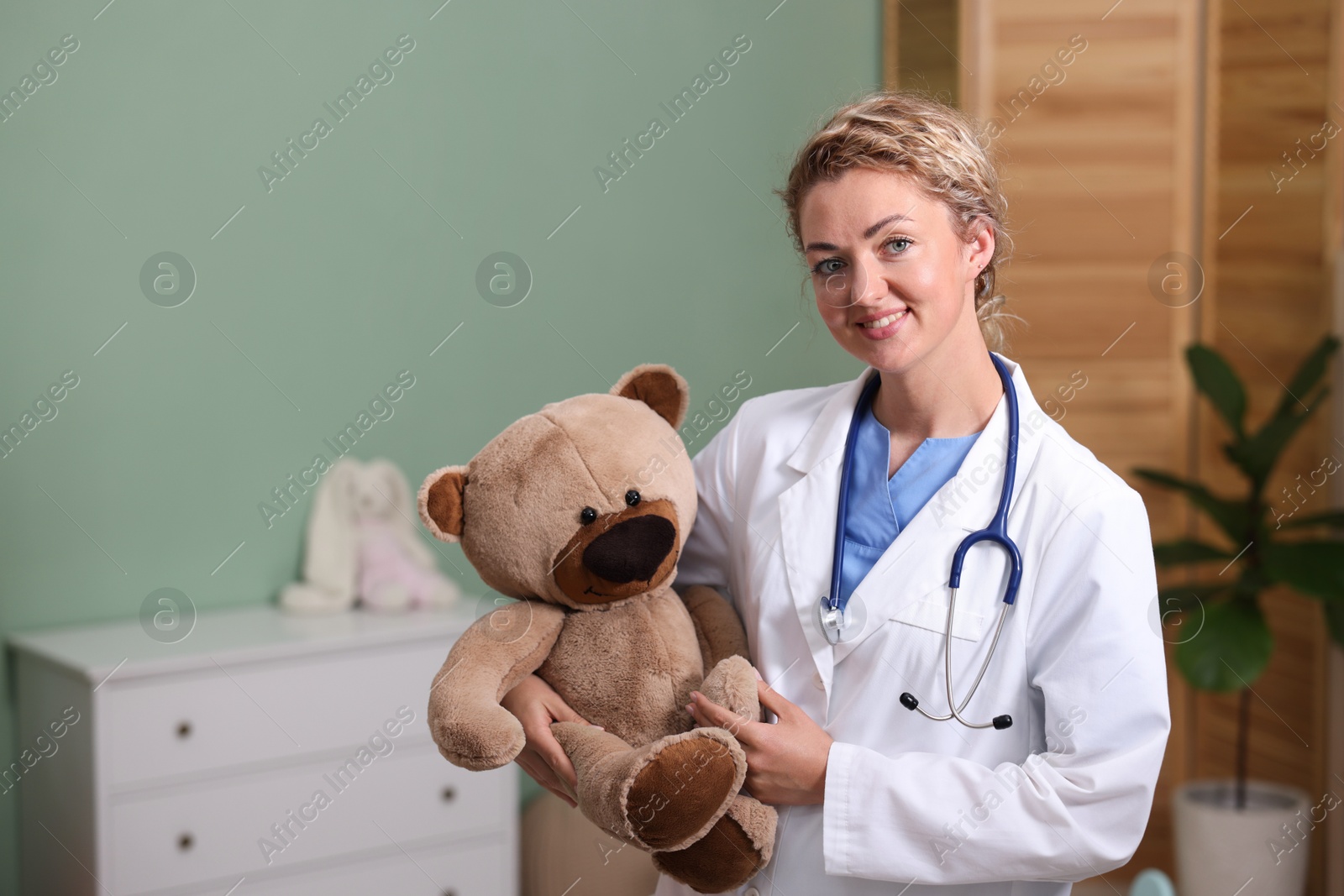 Pediatrician with toy bear in hospital. Space for text Photo of Pediatrician with toy bear in hospital. Space for text