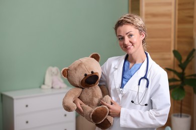 Photo of Pediatrician with toy bear in hospital. Space for text