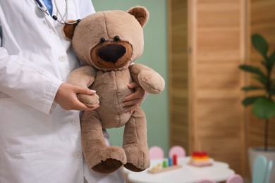 Photo of Pediatrician with toy bear in hospital, closeup. Space for text