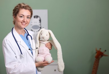 Photo of Pediatrician with toy bunny in hospital. Space for text