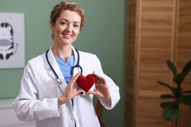 Photo of Professional pediatrician with heart model in clinic. Space for text