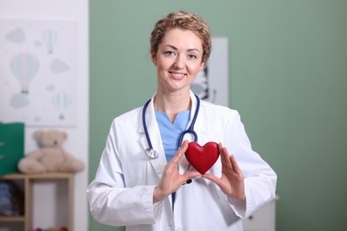 Photo of Professional pediatrician with heart model in clinic