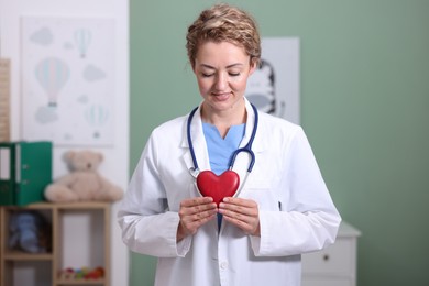 Photo of Professional pediatrician with heart model in clinic