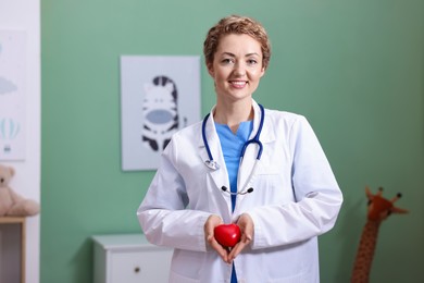Photo of Professional pediatrician with heart model in clinic