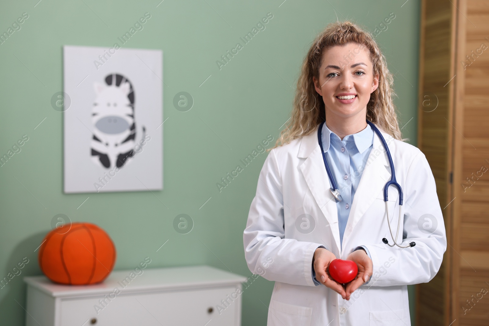 Professional pediatrician with heart model in clinic. Space for text Photo of Professional pediatrician with heart model in clinic. Space for text