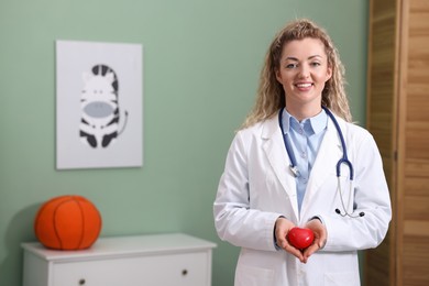 Photo of Professional pediatrician with heart model in clinic. Space for text