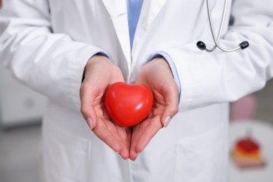 Photo of Pediatrician with heart model in clinic, closeup