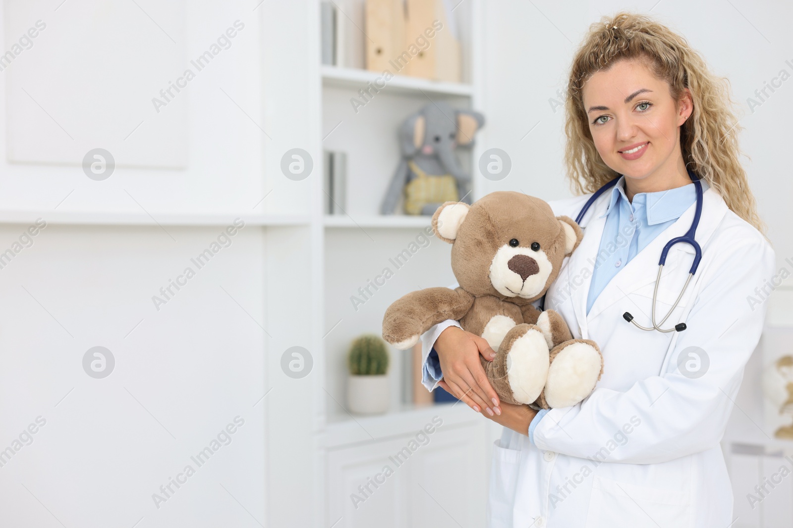 Pediatrician with toy bear in hospital. Space for text Photo of Pediatrician with toy bear in hospital. Space for text