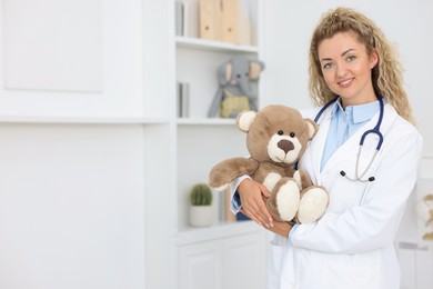 Photo of Pediatrician with toy bear in hospital. Space for text