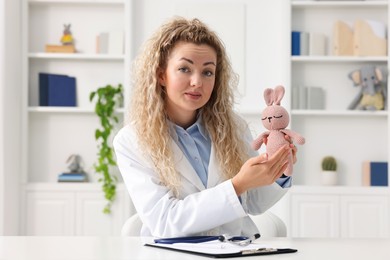 Photo of Pediatrician with toy bunny during video call, view from camera