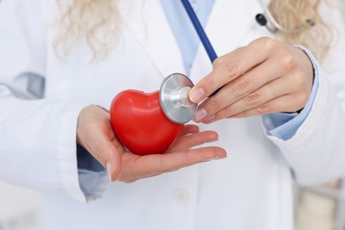 Photo of Pediatrician checking heartbeat of heart model in clinic, closeup