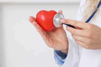 Photo of Pediatrician checking heartbeat of heart model in clinic, closeup