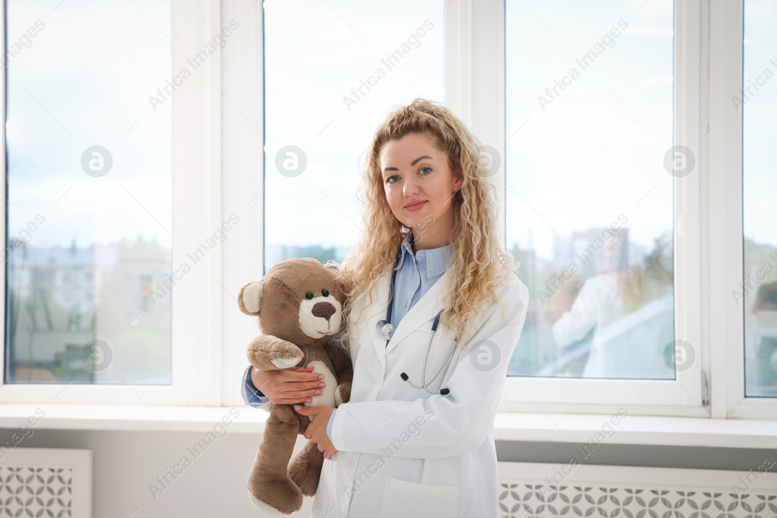 Pediatrician with toy bear near window in hospital Photo of Pediatrician with toy bear near window in hospital