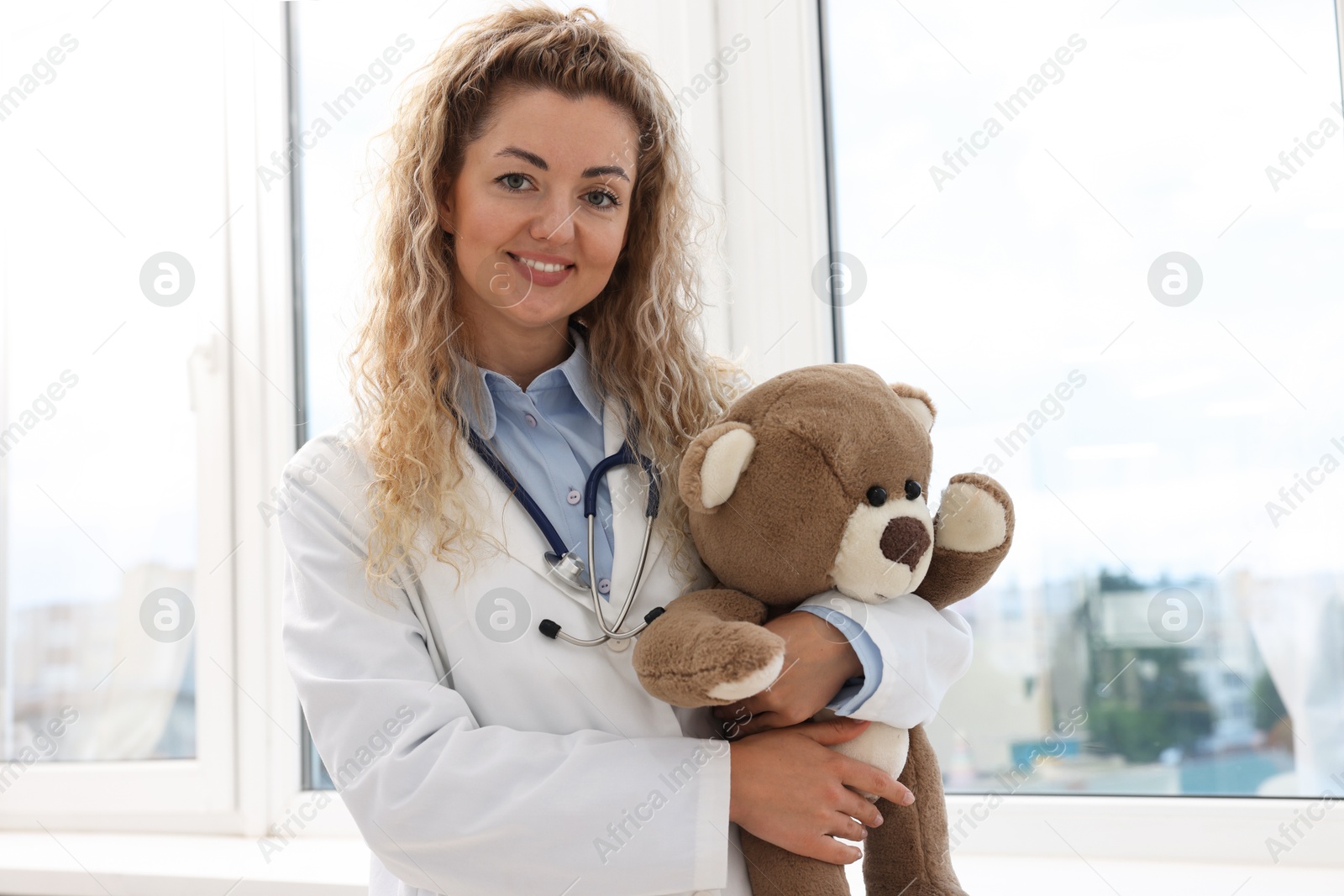 Pediatrician with toy bear near window in hospital Photo of Pediatrician with toy bear near window in hospital