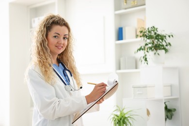 Photo of Portrait of professional pediatrician with stethoscope and clipboard in hospital. Space for text