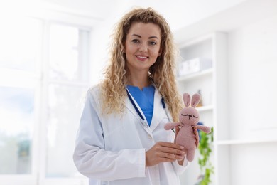 Photo of Professional pediatrician with toy bunny in hospital