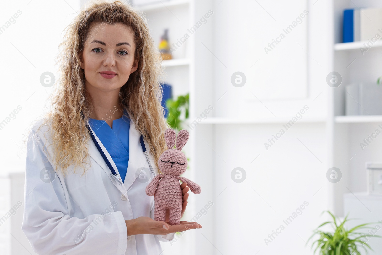 Professional pediatrician with toy bunny in hospital. Space for text Photo of Professional pediatrician with toy bunny in hospital. Space for text