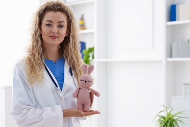 Photo of Professional pediatrician with toy bunny in hospital. Space for text