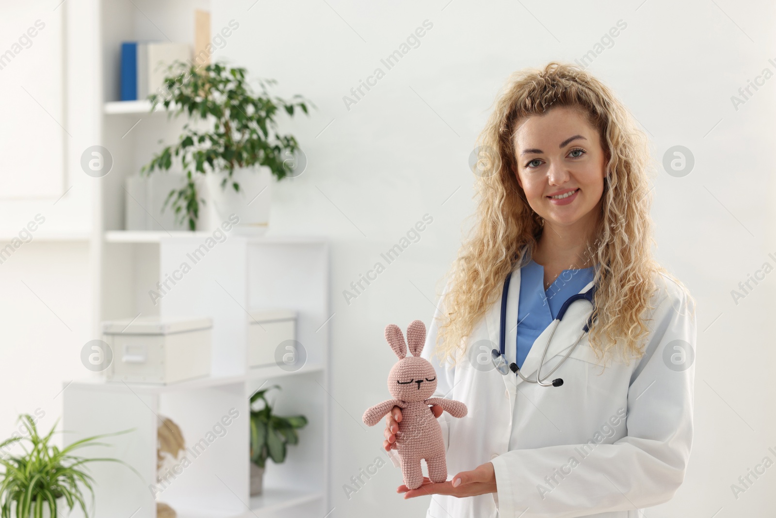 Professional pediatrician with toy bunny in hospital. Space for text Photo of Professional pediatrician with toy bunny in hospital. Space for text