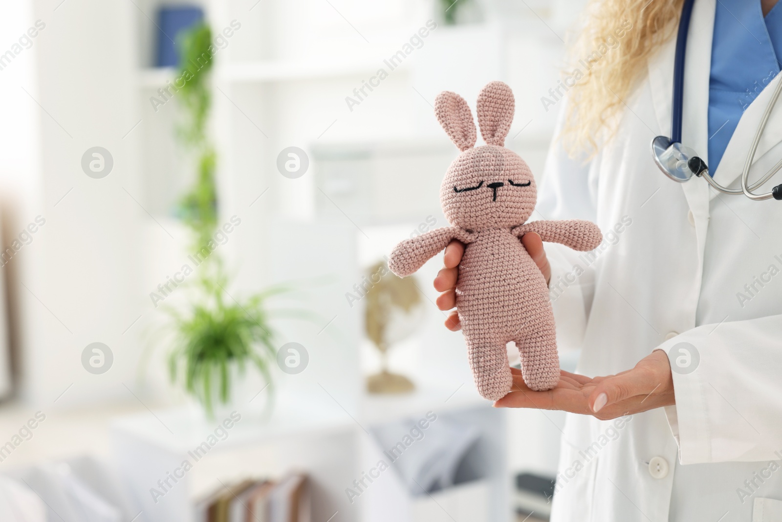Professional pediatrician with toy bunny in hospital, closeup. Space for text Photo of Professional pediatrician with toy bunny in hospital, closeup. Space for text