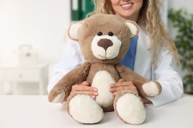 Photo of Pediatrician with toy bear at desk in hospital, closeup