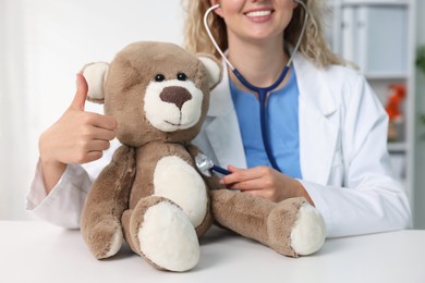 Photo of Pediatrician checking heartbeat of toy bear at desk in hospital, closeup