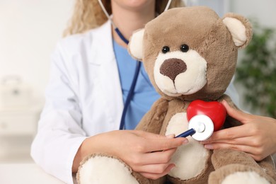 Photo of Pediatrician checking heartbeat of toy bear in hospital, closeup