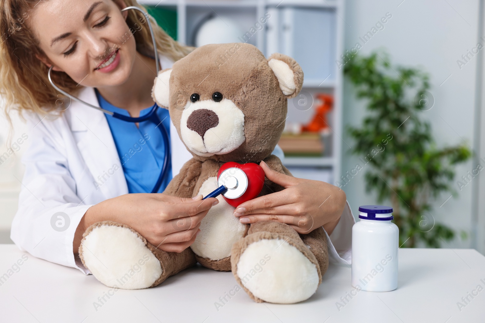 Pediatrician checking heartbeat of toy bear at desk in hospital Photo of Pediatrician checking heartbeat of toy bear at desk in hospital