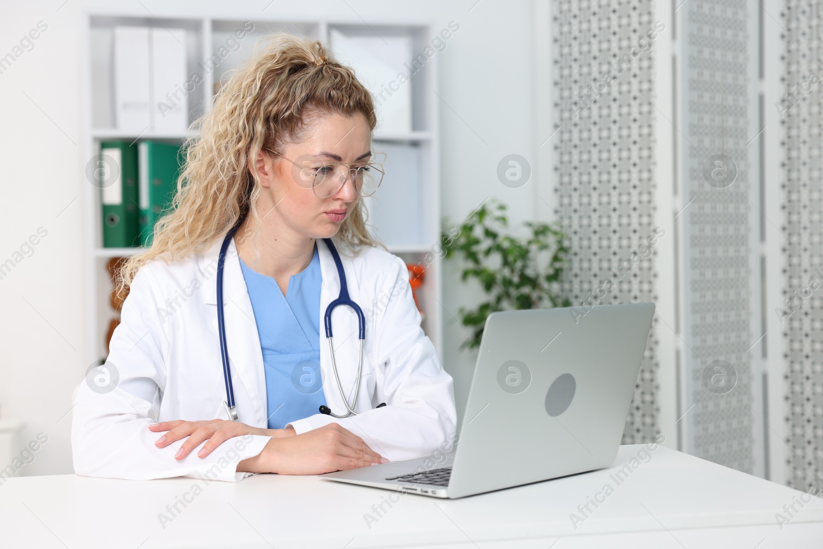 Professional pediatrician working on laptop at desk in clinic Photo of Professional pediatrician working on laptop at desk in clinic