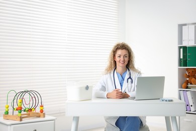 Photo of Professional pediatrician working at desk in clinic