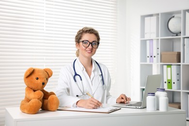 Photo of Pediatrician working on laptop at desk in hospital