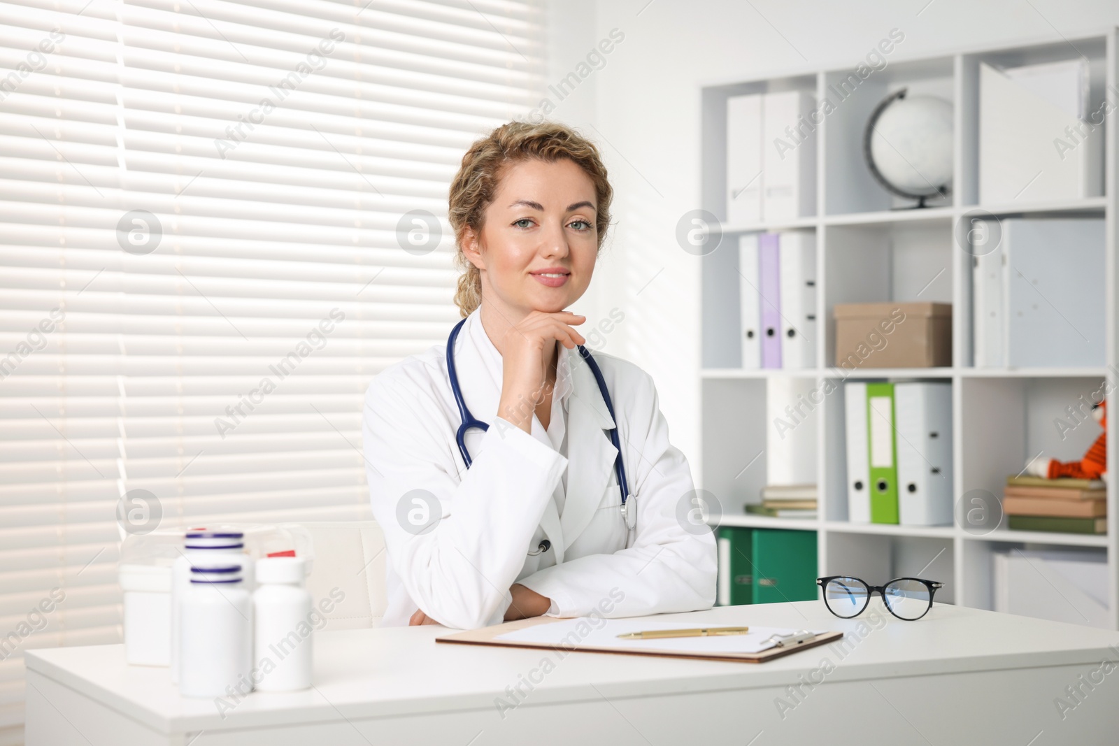Professional pediatrician working at desk in clinic Photo of Professional pediatrician working at desk in clinic