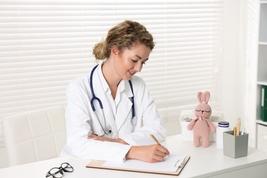 Photo of Professional pediatrician working at desk in clinic