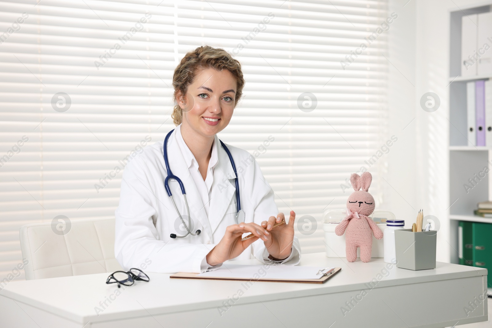 Professional pediatrician working at desk in clinic Photo of Professional pediatrician working at desk in clinic