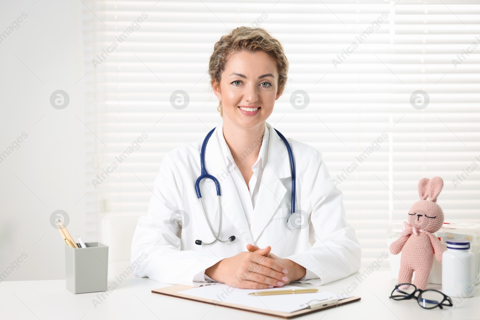 Professional pediatrician working at desk in clinic Photo of Professional pediatrician working at desk in clinic