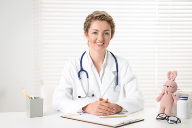 Photo of Professional pediatrician working at desk in clinic