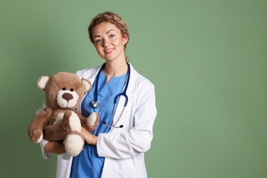 Photo of Pediatrician with toy bear on olive background. Space for text